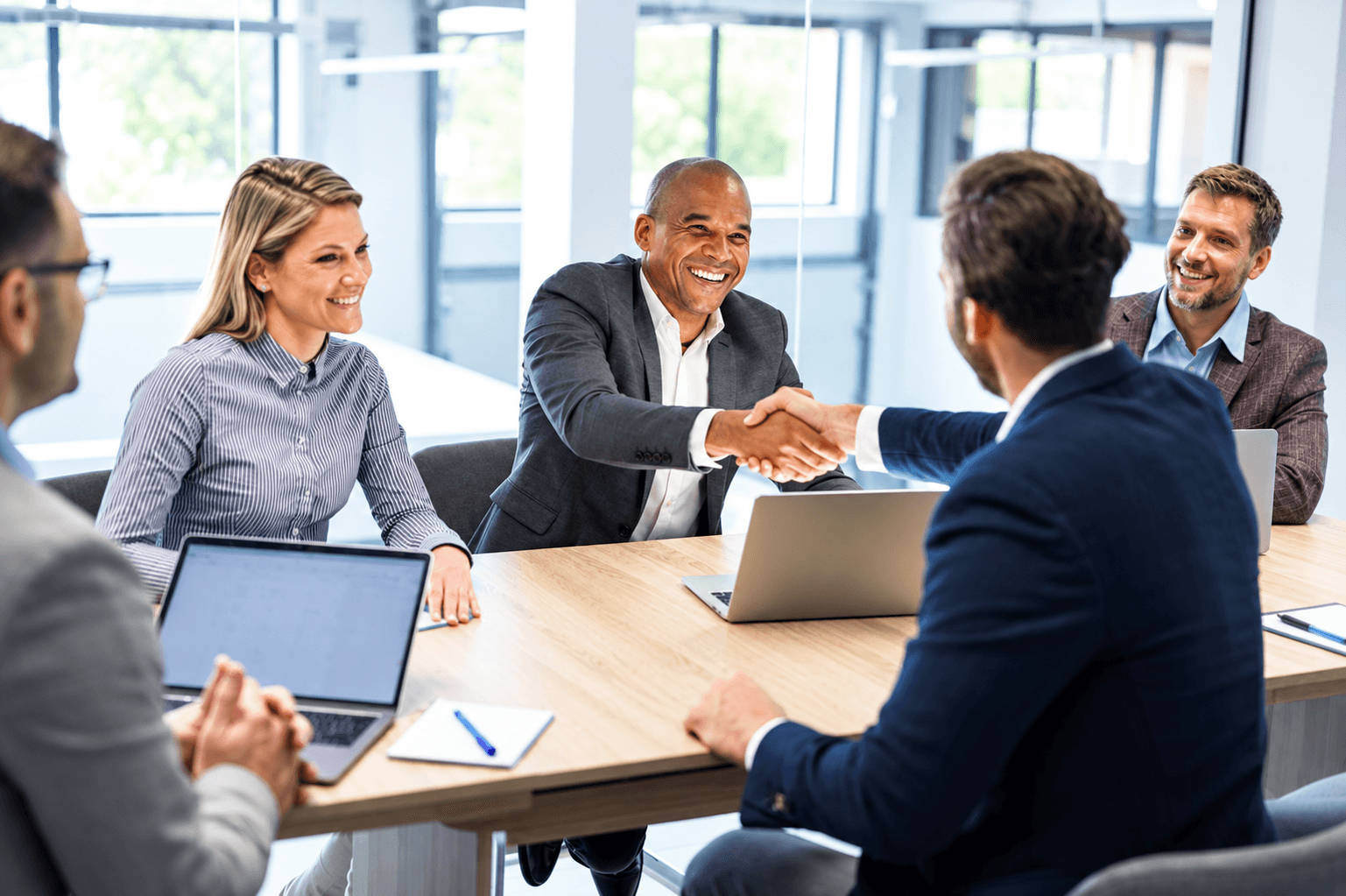 Two teams shaking hands across a meeting table