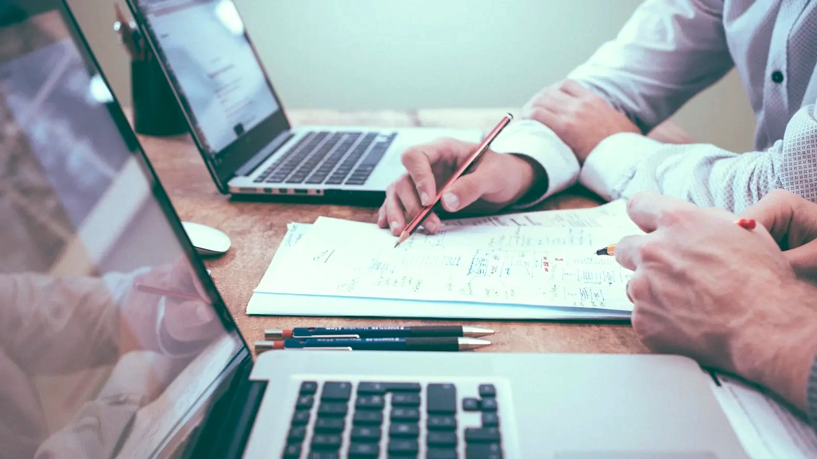 Notes and laptops open on a desk during a planning session